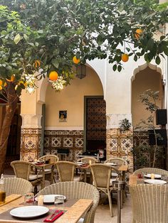 an outdoor dining area with wicker chairs and oranges hanging from the trees above