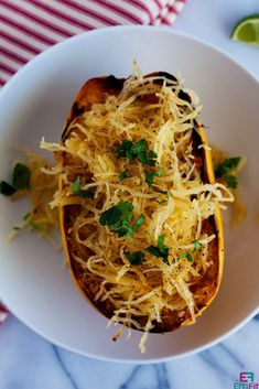 a white bowl filled with spaghetti and cheese on top of a blue striped table cloth