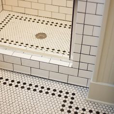 a bathroom with black and white tile on the floor, shower stall door and toilet