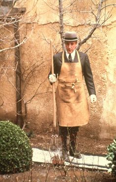 a man in an apron and hat holding a shovel