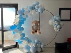 a teddy bear hanging from a circle with balloons