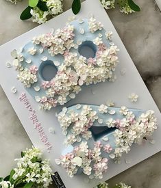 two decorated doughnuts sitting on top of a white table next to some flowers