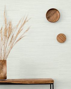 three wooden plates mounted to the side of a wall next to a table with a plant in it