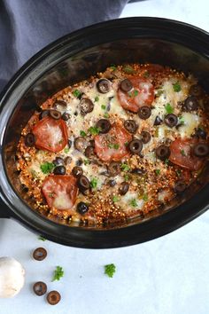 a close up of a casserole dish with olives, tomatoes and mushrooms