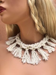 a mannequin wearing a white necklace with tassels on it's neck