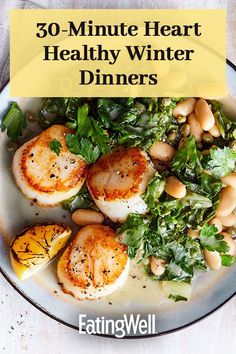 a white plate topped with scallops and greens