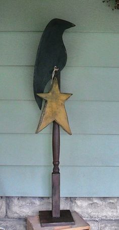 a metal bird on top of a wooden pole with a star hanging from it's side