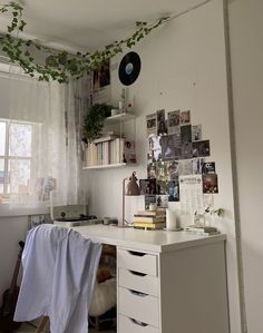 a white desk topped with lots of drawers under a window next to a book shelf