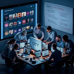 a group of people sitting around a table with laptops and tablets in front of them