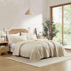 a bed with white sheets and pillows in a room next to a large open window