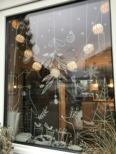 a window with christmas decorations drawn on it and lights hanging from the windowsills