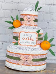 a three tiered cake with oranges on the side and a little cute sign