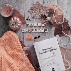 an open book sitting on top of a wooden floor next to autumn leaves and candles