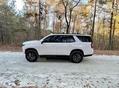 a white suv is parked in the snow