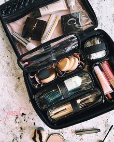 an open suitcase filled with makeup and other items on the ground next to a pair of scissors