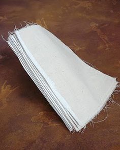 a stack of white napkins sitting on top of a brown table next to a cup