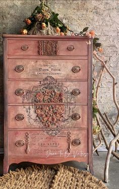 an old dresser is painted pink and has ornate carvings on the top, along with flowers