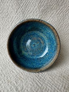 a blue bowl sitting on top of a white cloth covered table next to a wall