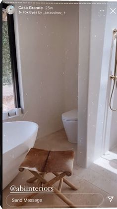 a white bathroom with a wooden stool in front of the tub