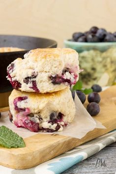 two blueberry scones stacked on top of each other next to a bowl of berries