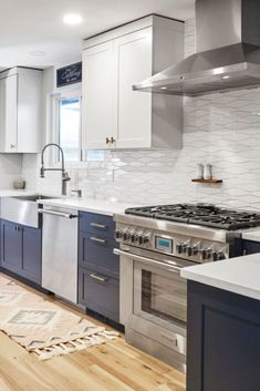 a kitchen with stainless steel appliances and blue cabinets, white counter tops and wooden floors