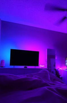 a bedroom with purple lighting and a flat screen tv mounted on the wall above it