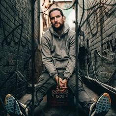 a man sitting on the ground in an alleyway with his feet up and holding a suitcase