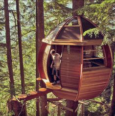 a tree house in the middle of some trees with people standing inside and looking at it