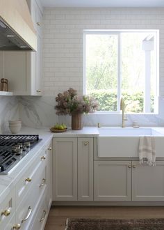 a kitchen with white cabinets and marble counter tops, along with a window over the sink