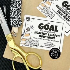 a pair of gold scissors sitting on top of a piece of paper next to some stickers