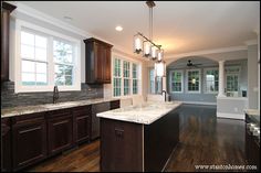 an empty kitchen with wood floors and granite counter tops, along with dark wooden cabinets