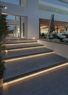 the stairs are lit up with leds in front of a modern house at dusk