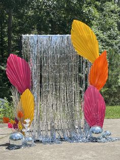 colorful umbrellas and streamers are displayed in front of a metal structure on the ground