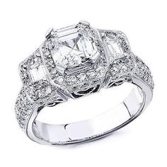 a diamond ring with three stones on the sides and an oval center surrounded by smaller diamonds