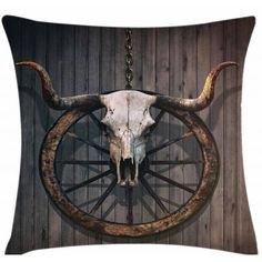 a cow skull hanging from a chain on a wooden wall next to a bicycle wheel