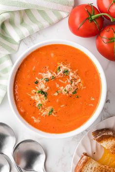 a bowl of tomato soup with bread and tomatoes