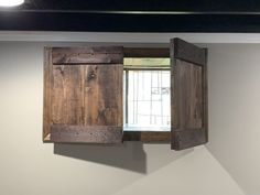 an open window in the corner of a white room with wooden shutters and bars