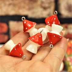 small red and white earrings are being held in someone's hand with their fingers