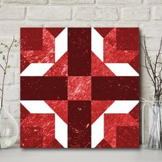 a red and white wall hanging on a brick wall next to vases with flowers