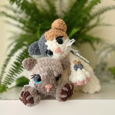 two crocheted stuffed animals sitting on top of a table next to a potted plant