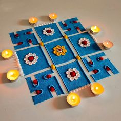 a table topped with candles next to a blue mat covered in flowers and circles on top of it