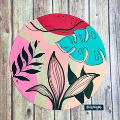 a colorful plate with leaves on it sitting on a wooden table next to a sticker