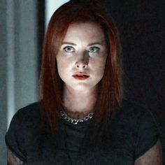 a woman with red hair is staring at the camera