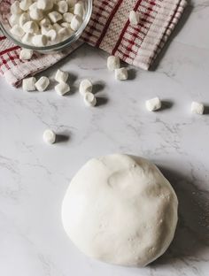 marshmallows are scattered around a doughnut on a white counter with a red and white towel