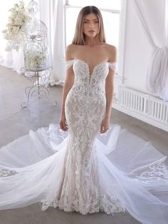 a woman in a white wedding dress standing next to a birdcage with flowers on it