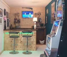 two chairs sitting in front of a bar with a tv on the wall behind it