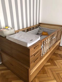 a baby crib in the corner of a room next to a wall with stripes on it