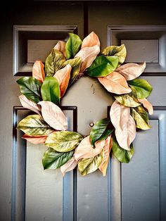 a wreath is hanging on the front door with green and orange leaves attached to it