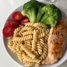 a white plate topped with pasta, broccoli and chicken next to cherry tomatoes