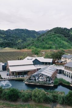 an aerial view of a building with a pond in the foreground and mountains in the background